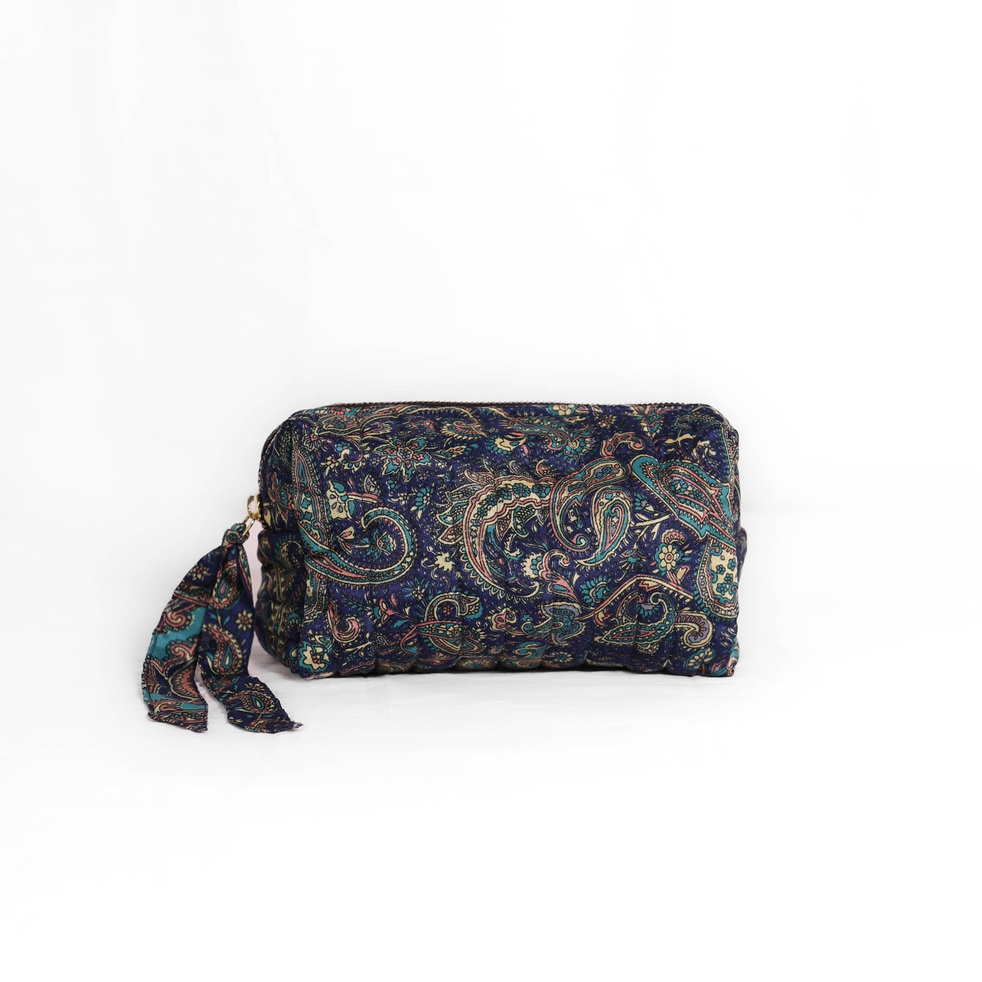 Quilted dumpling bag made from repurposed vintage sari fabric with stitched detailing and a structured rectangular shape. The bag features a zip closure and a fabric tie
