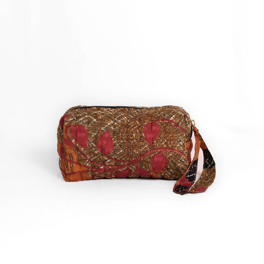 Quilted dumpling bag made from repurposed vintage sari fabric with stitched detailing and a structured rectangular shape. The bag features a zip closure and a fabric tie
