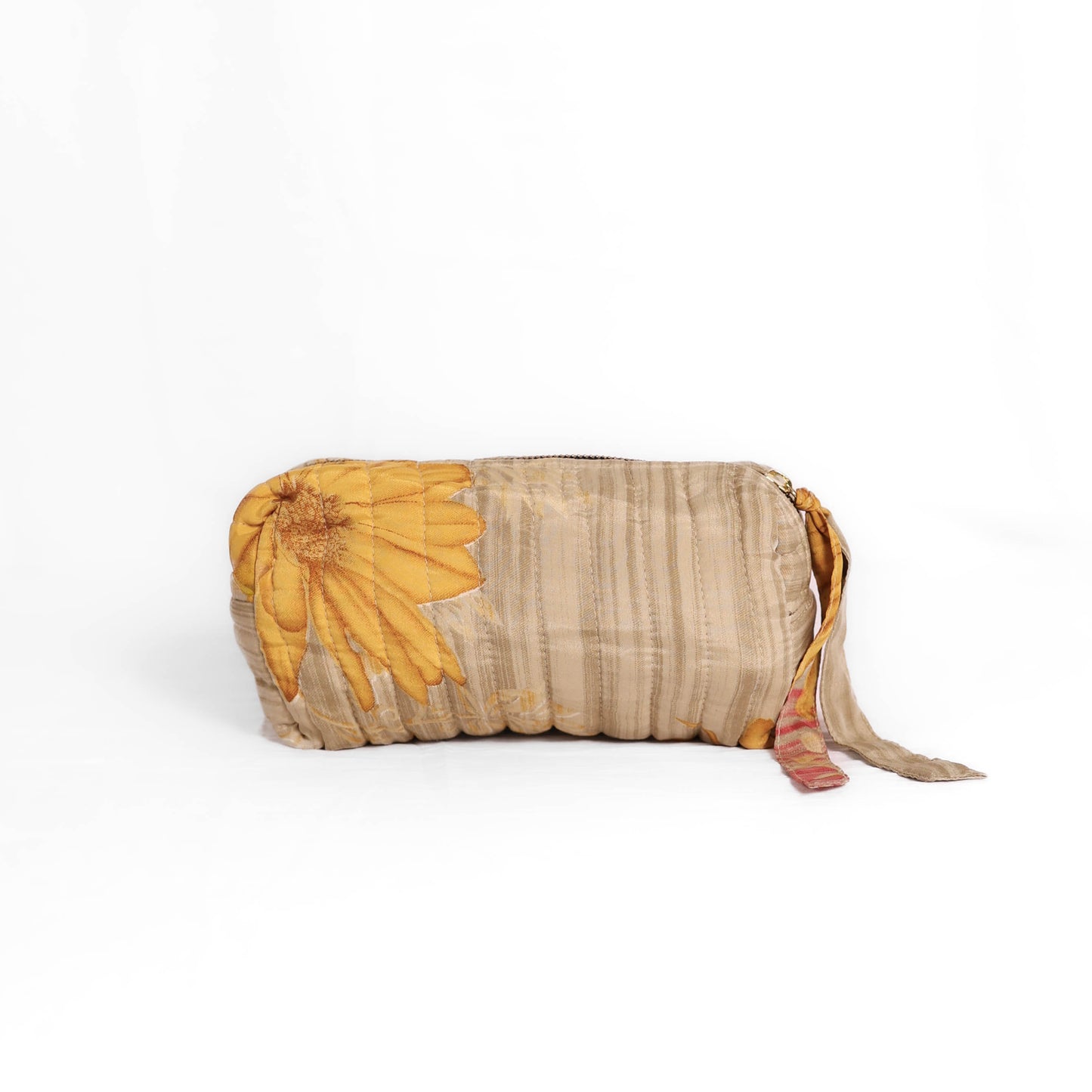 Quilted dumpling bag made from repurposed vintage sari fabric with stitched detailing and a structured rectangular shape. The bag features a zip closure and a fabric tie
