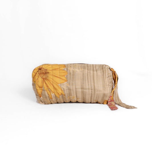 Quilted dumpling bag made from repurposed vintage sari fabric with stitched detailing and a structured rectangular shape. The bag features a zip closure and a fabric tie
