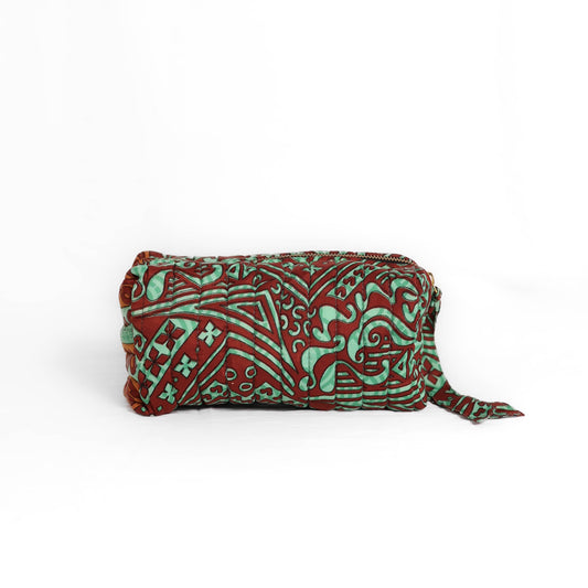 Quilted dumpling bag made from repurposed vintage sari fabric with stitched detailing and a structured rectangular shape. The bag features a zip closure and a fabric tie
