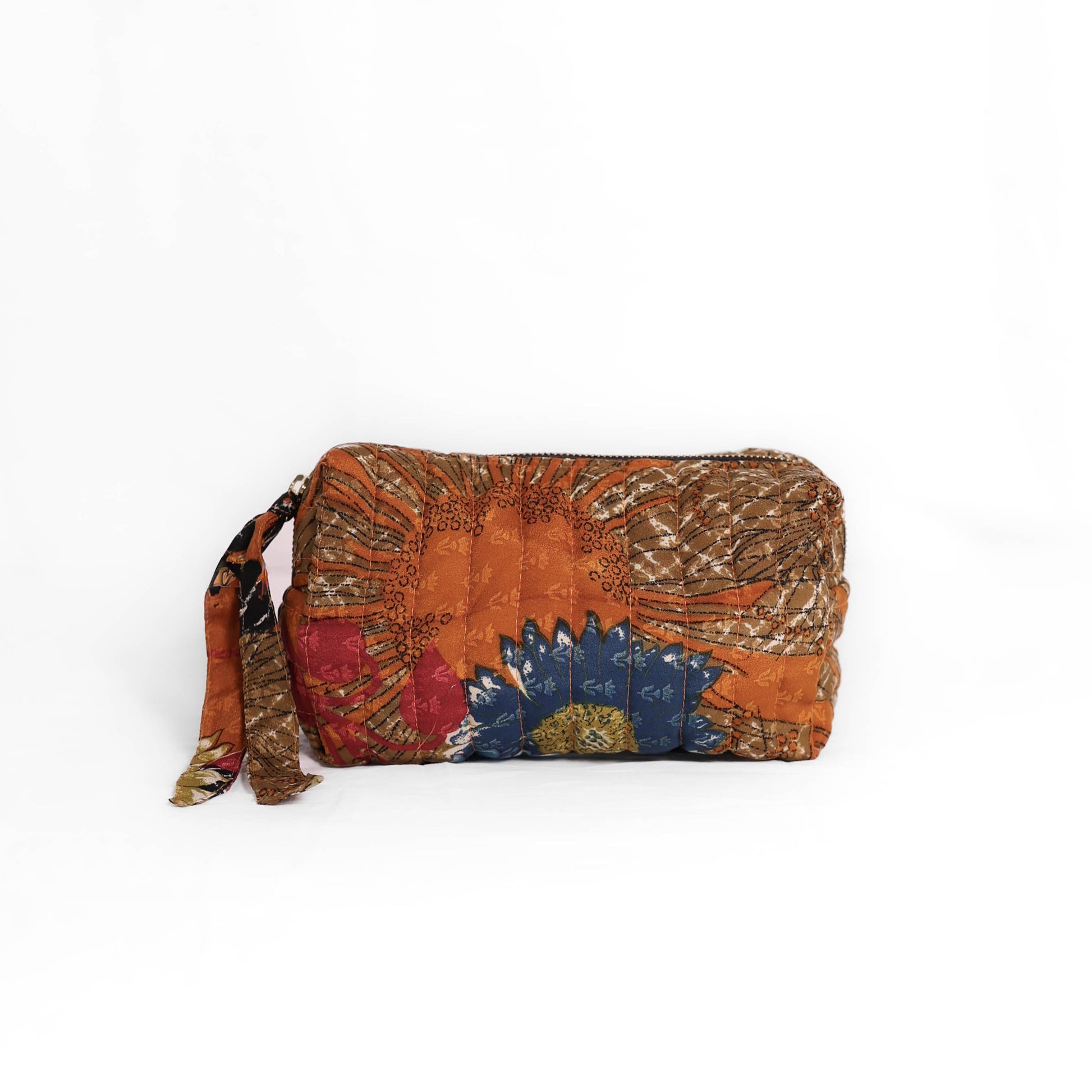 Quilted dumpling bag made from repurposed vintage sari fabric with stitched detailing and a structured rectangular shape. The bag features a zip closure and a fabric tie
