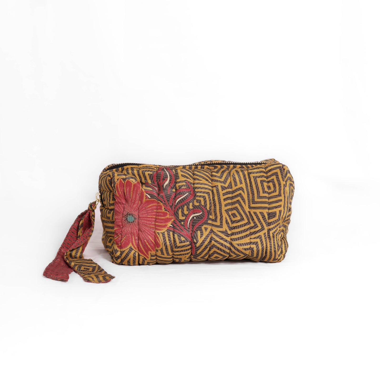 Quilted dumpling bag made from repurposed vintage sari fabric with stitched detailing and a structured rectangular shape. The bag features a zip closure and a fabric tie
