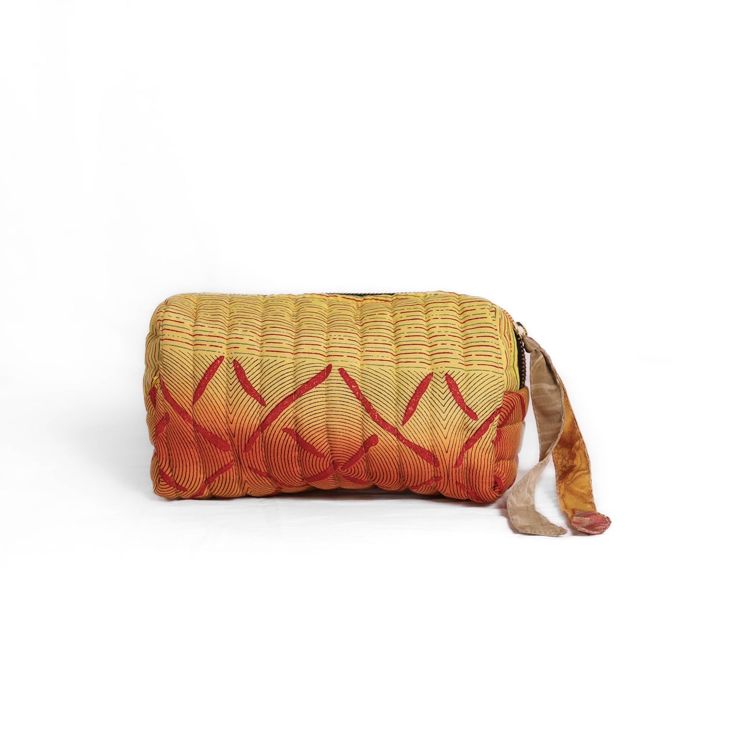 Quilted dumpling bag made from repurposed vintage sari fabric with stitched detailing and a structured rectangular shape. The bag features a zip closure and a fabric tie
