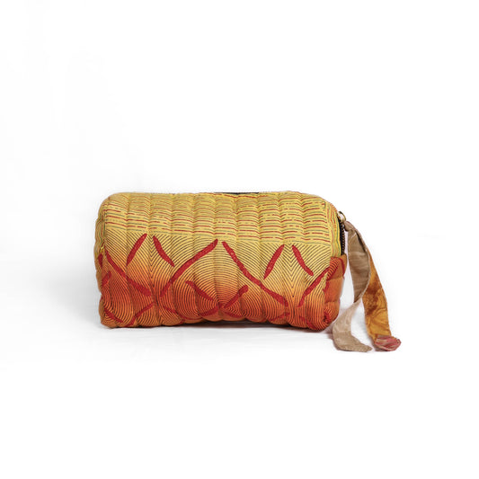 Quilted dumpling bag made from repurposed vintage sari fabric with stitched detailing and a structured rectangular shape. The bag features a zip closure and a fabric tie
