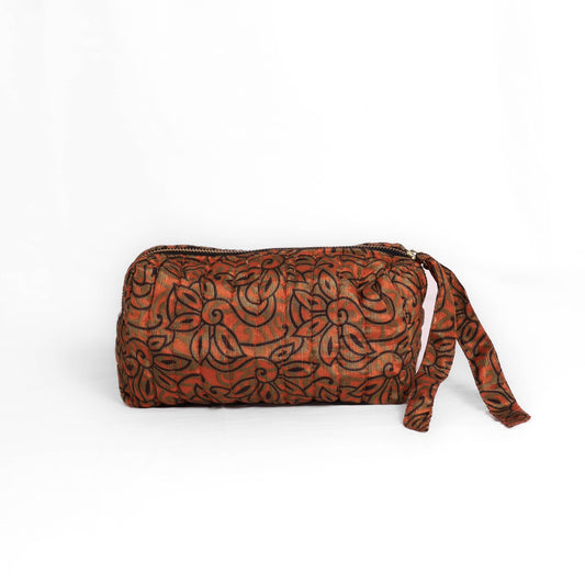 Quilted dumpling bag made from repurposed vintage sari fabric with stitched detailing and a structured rectangular shape. The bag features a zip closure and a fabric tie
