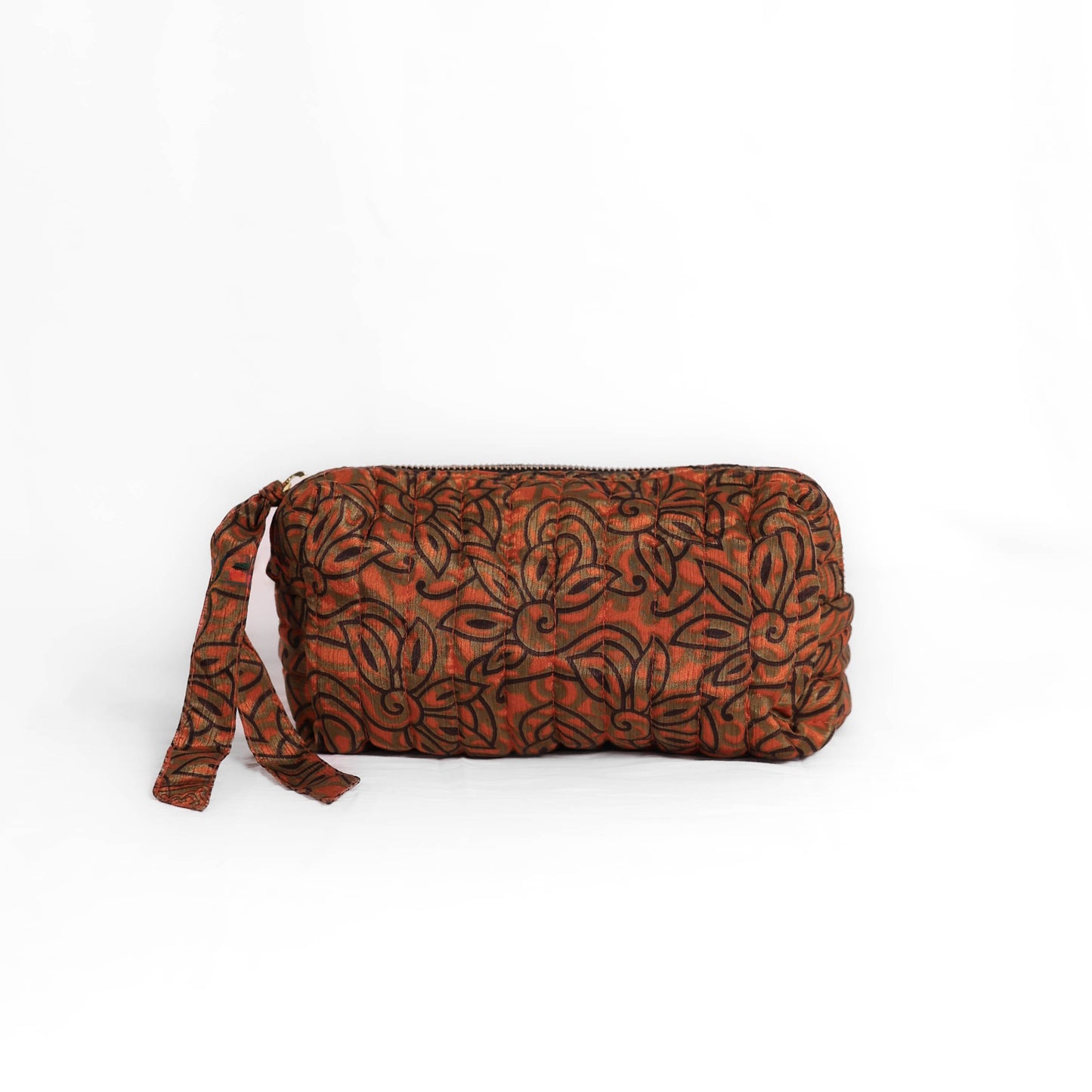 Quilted dumpling bag made from repurposed vintage sari fabric with stitched detailing and a structured rectangular shape. The bag features a zip closure and a fabric tie
