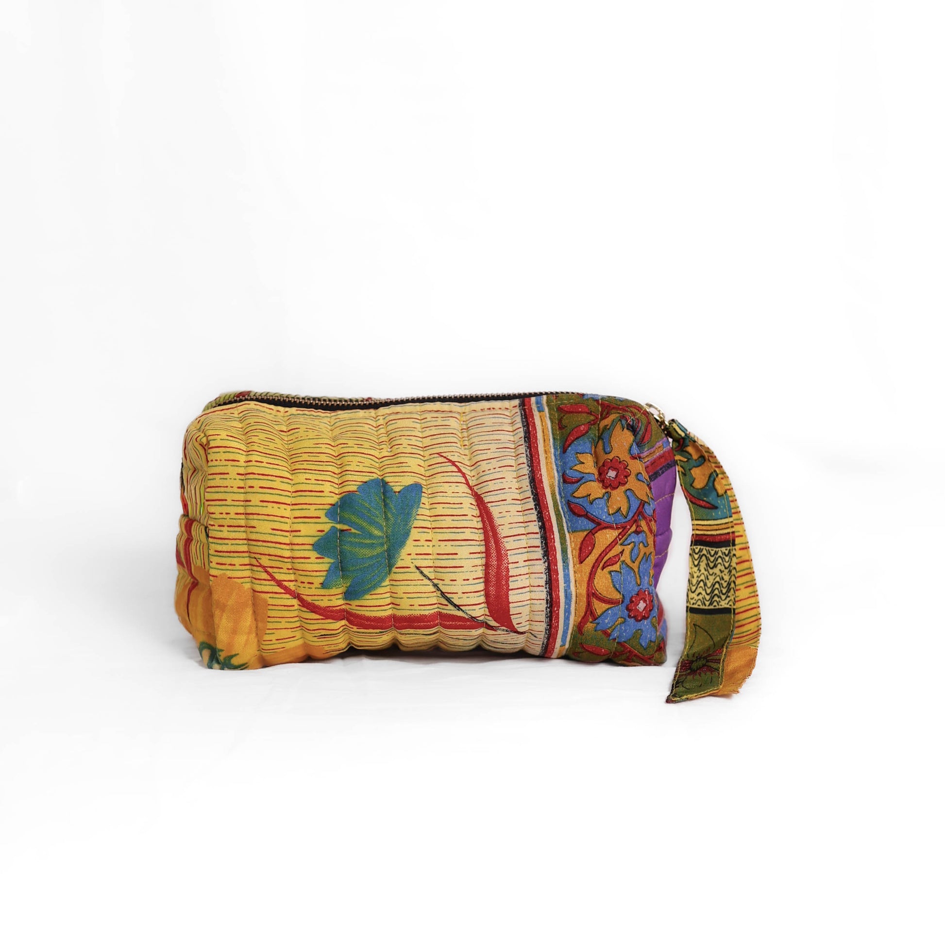 Quilted dumpling bag made from repurposed vintage sari fabric with stitched detailing and a structured rectangular shape. The bag features a zip closure and a fabric tie
