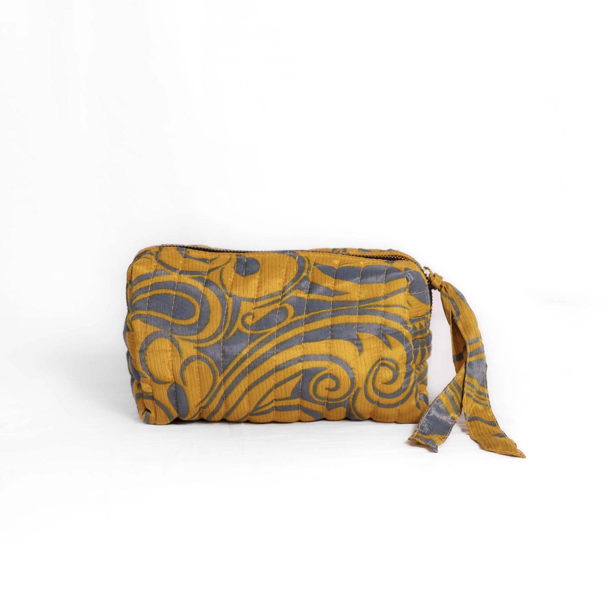 Quilted dumpling bag made from repurposed vintage sari fabric with stitched detailing and a structured rectangular shape. The bag features a zip closure and a fabric tie
