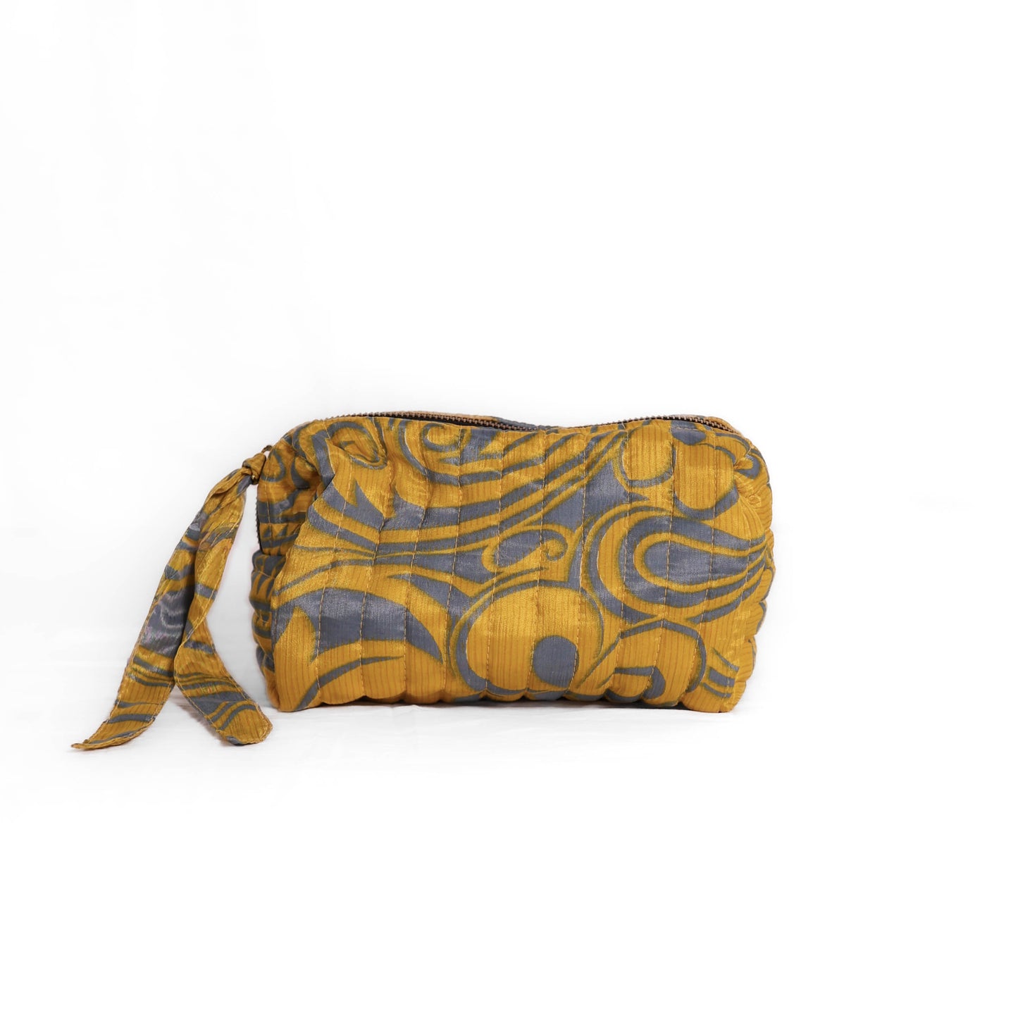 Quilted dumpling bag made from repurposed vintage sari fabric with stitched detailing and a structured rectangular shape. The bag features a zip closure and a fabric tie
