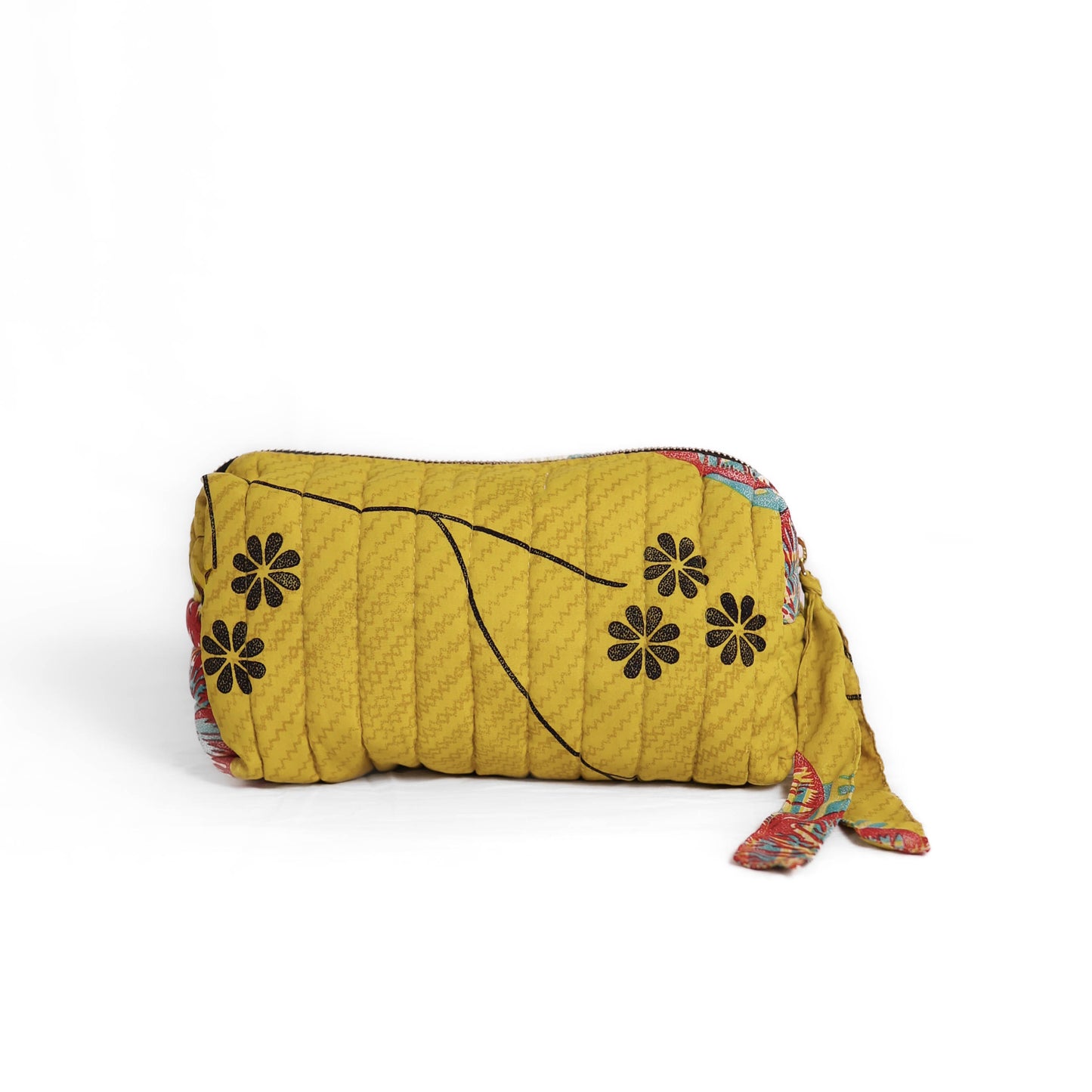 Quilted dumpling bag made from repurposed vintage sari fabric with stitched detailing and a structured rectangular shape. The bag features a zip closure and a fabric tie
